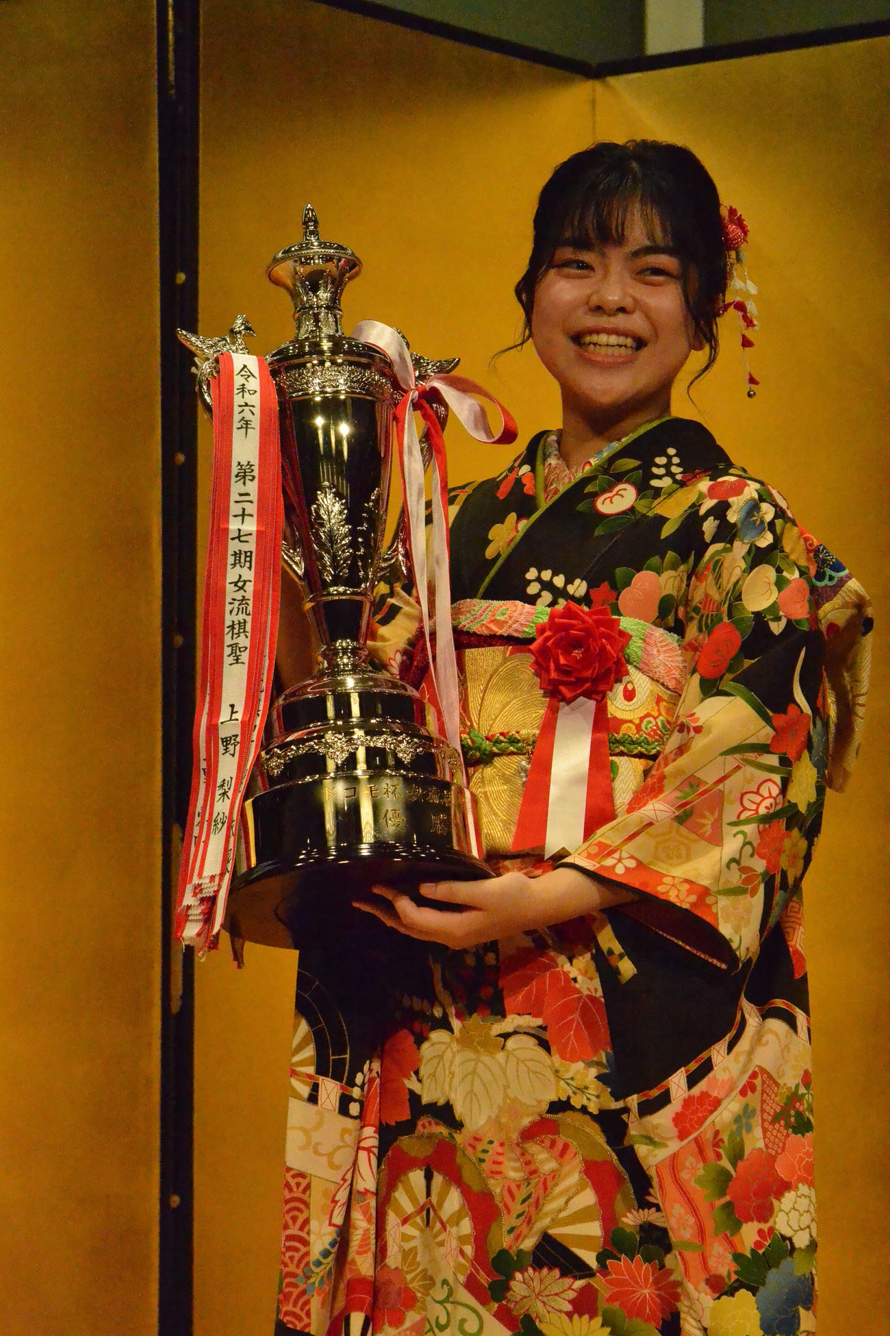 賞杯を手に「重いです」と笑顔を見せる上野梨紗女流棋聖