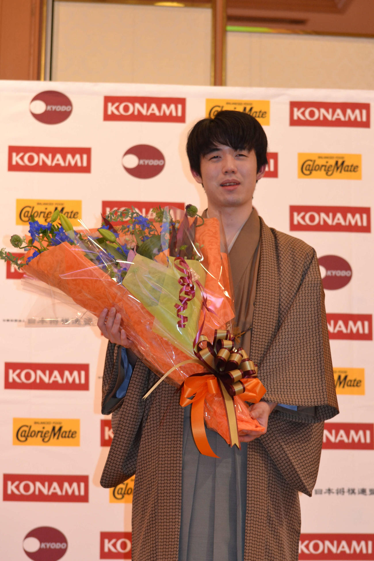 初防衛して会見場で花束を手にする藤井聡太棋王