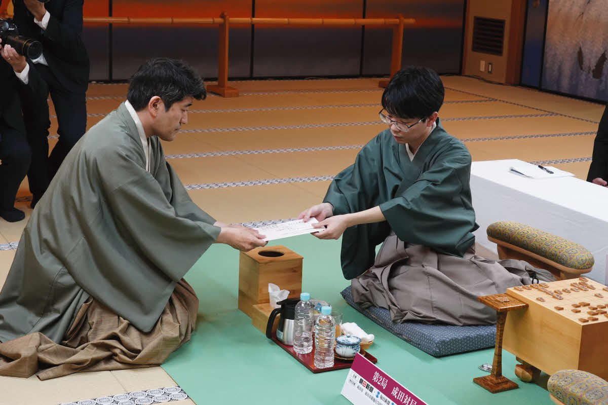 立会人の森内俊之九段（左）に封じ手の入った封筒を手渡す豊島将之九段（右、日本将棋連盟提供）