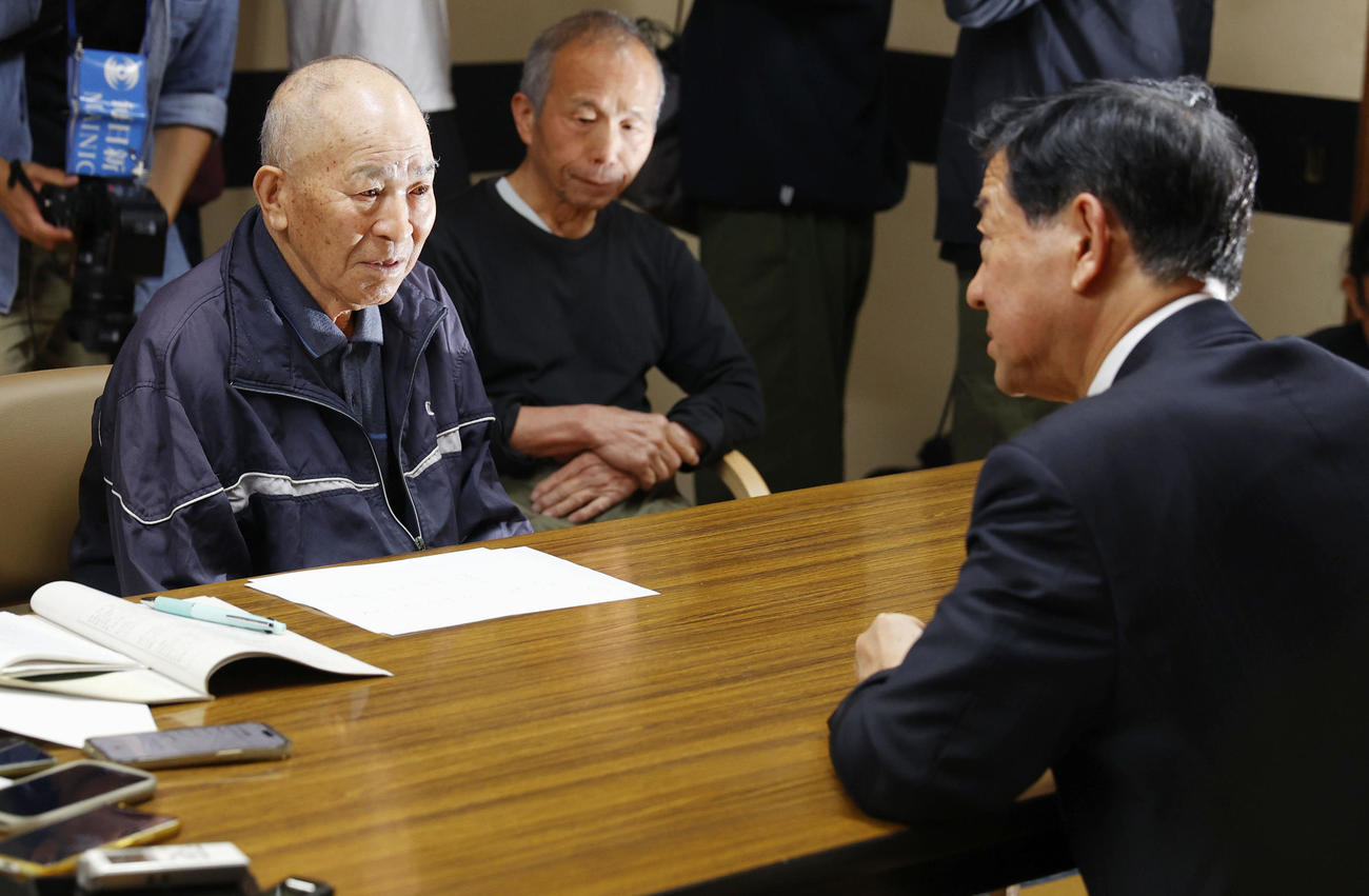 謝罪に訪れた伊藤環境相（右）と話す水俣病患者連合の松崎重光副会長＝8日午後、熊本県水俣市（共同）