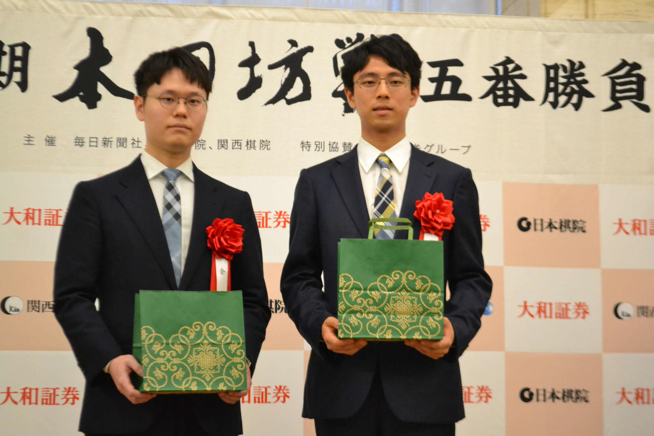 国宝尾形光琳のすずり箱をモチーフにした印伝の名刺入れとがまぐち、印鑑ケースの入った記念品を手にする余正麒八段（左）と一力遼本因坊（右）