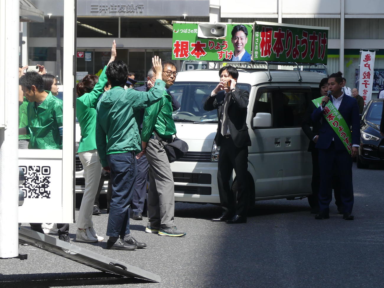 衆院東京15区補選で、手を振る乙武洋匡氏のスタッフ（手前）の前で演説する根本良輔元候補（2024年4月16日撮影）