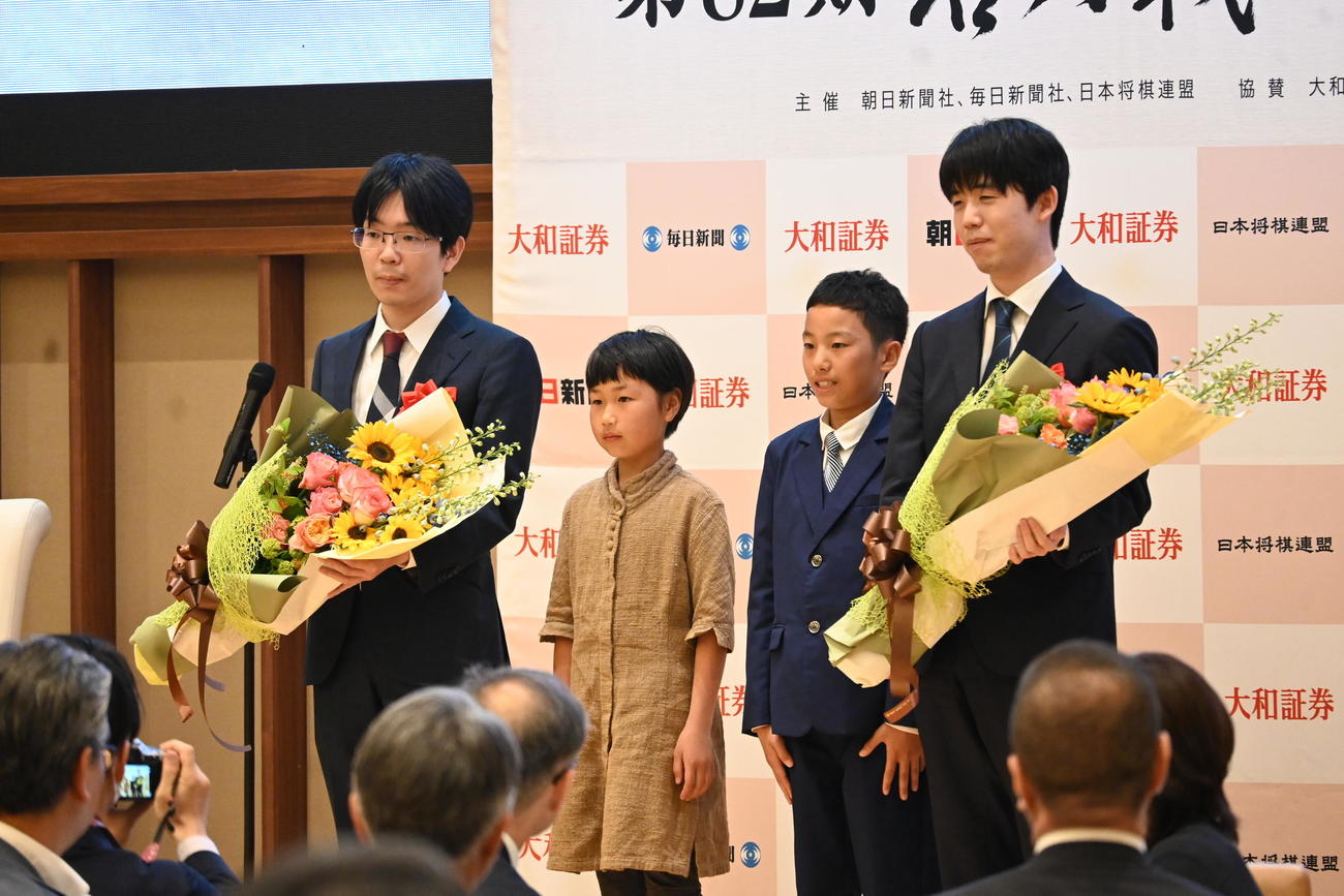 大分県別府市内で行われた名人戦7番勝負第4局の前夜祭で地元の子どもから花束を贈呈される藤井聡太名人（右）豊島将之九段（撮影・松浦隆司）