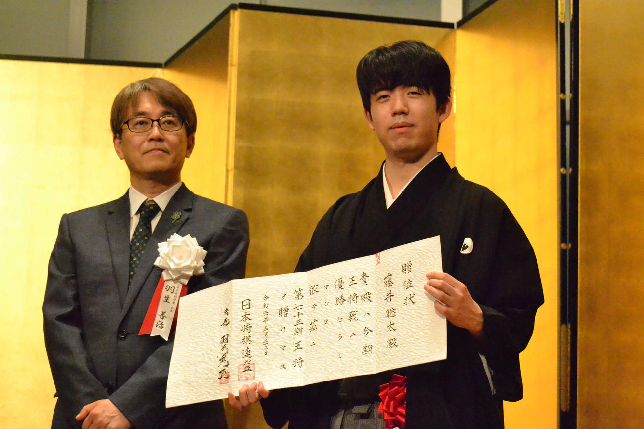 日本将棋連盟の羽生善治会長（左）の横で贈位状を手にする藤井聡太王将（右）