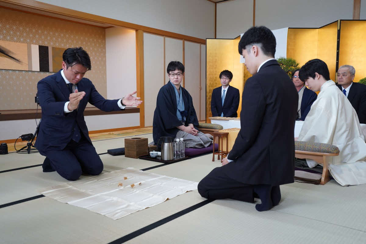 先手後手を決める振り駒はと金が3枚出て山崎隆之八段（左から2人目）が先手と決まった（右は後手の藤井聡太棋聖、日本将棋連盟提供）