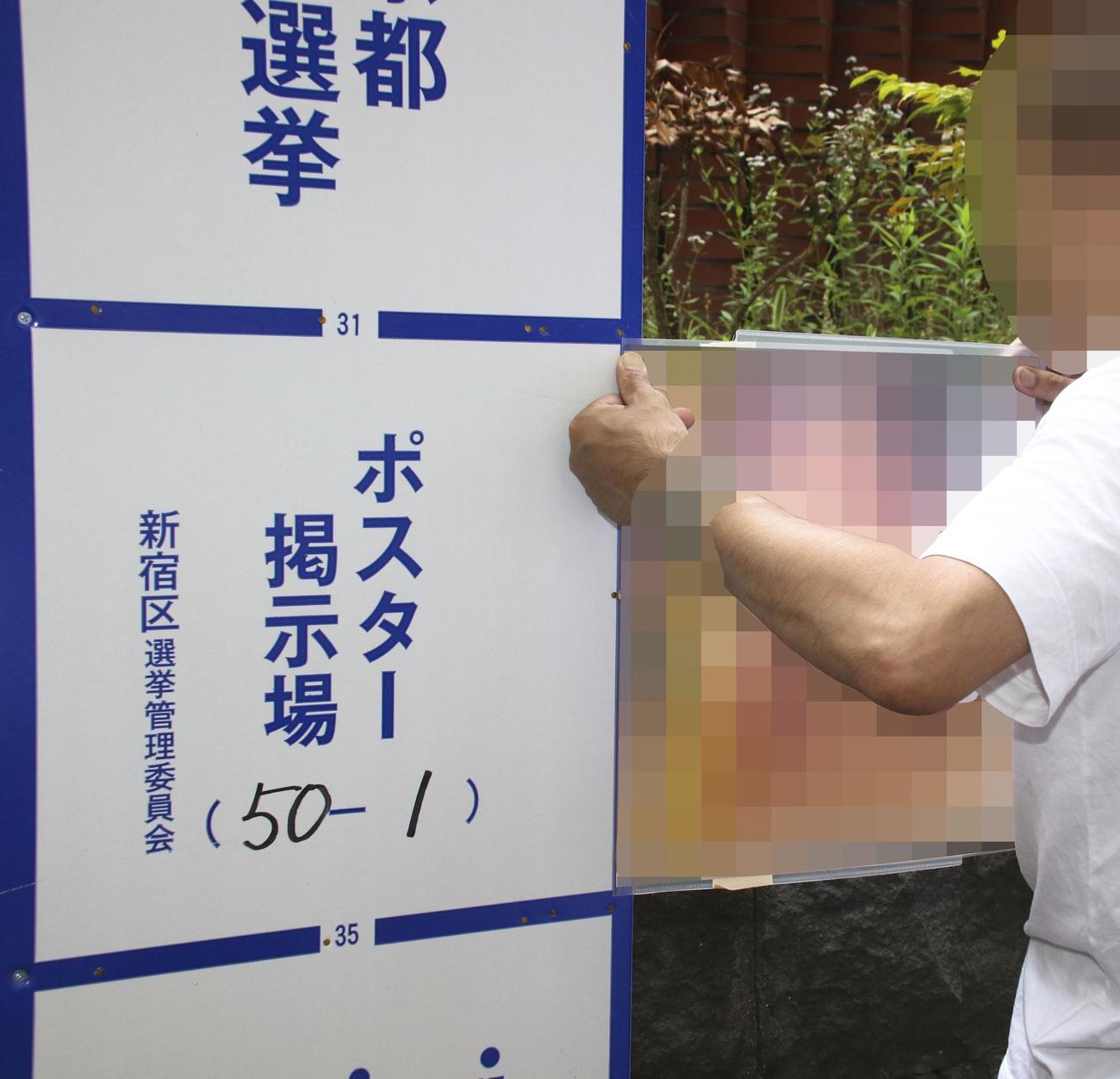東京都知事選の掲示板の外にクリアファイルに挟んだポスターを固定する候補者（共同）