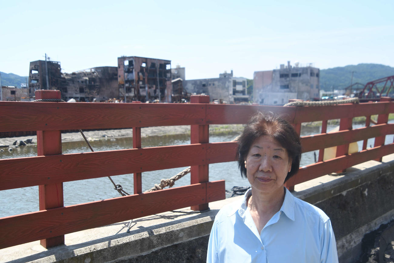 輪島市街地で民宿「寅さん」を営む寅松征子さん。背後には焼け野原と化した輪島朝市が見える（撮影・平山連）