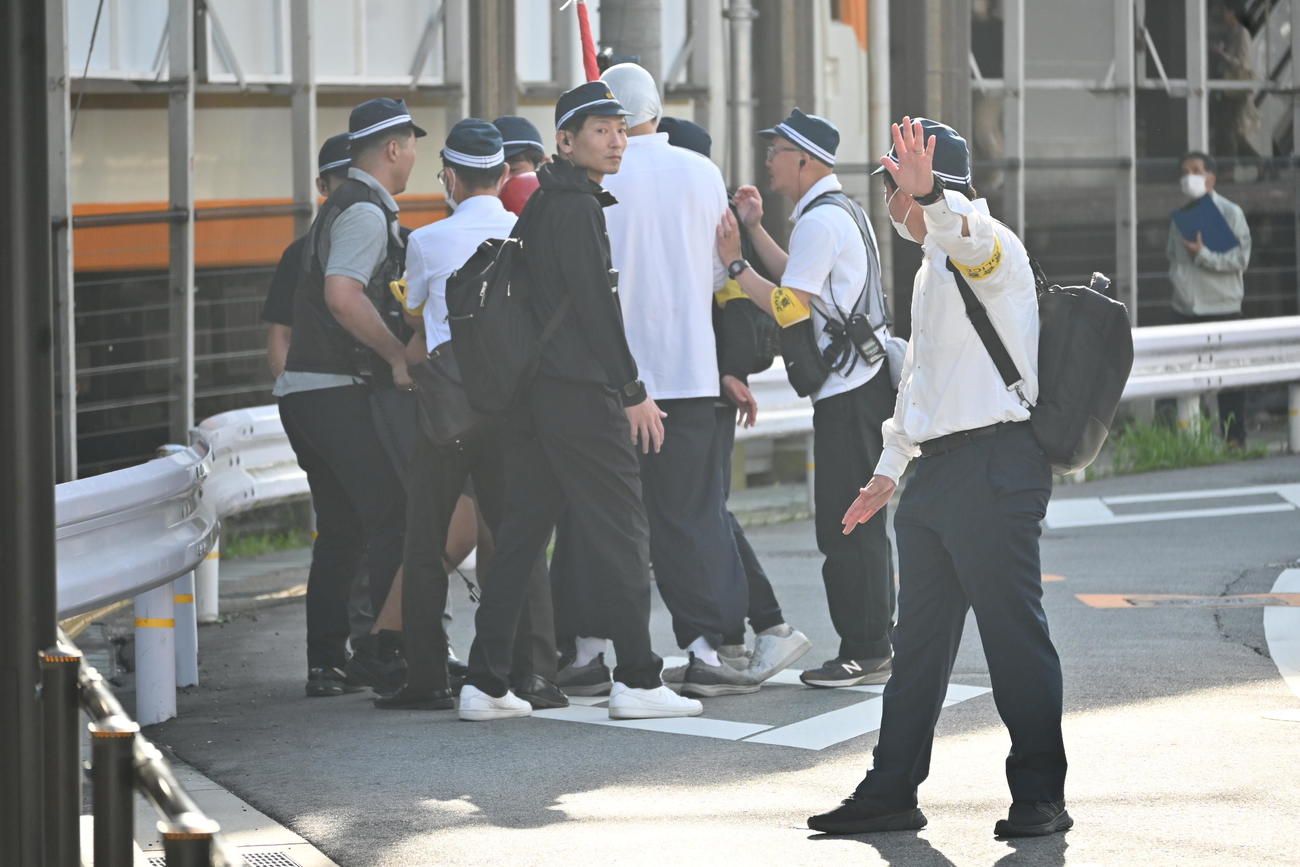 現場となった奈良・大和西大寺駅前に設置された献花台の近くで赤いヘルメットの男性と上半身白ずくめの男性が警察官をもみ合いになり騒然（撮影・松浦隆司）