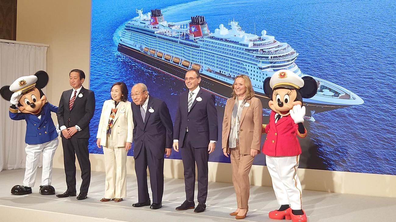 オリエンタルランドの新事業「ディズニークルーズ」の会見で登壇した左からミッキーマウス、吉田謙次社長、高野由美子会長、加賀見俊夫取締役、トーマス・マズルーム氏、シャロン・シスキー氏、ミニーマウス