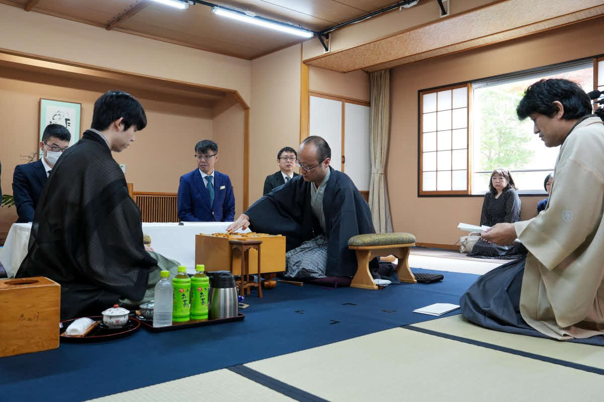 藤井聡太王位（左）に渡辺明九段（中央）が挑戦する王位戦第2局は立会人の森内俊之九段（右）が封じ手を開封して2日目がスタート（日本将棋連盟提供）