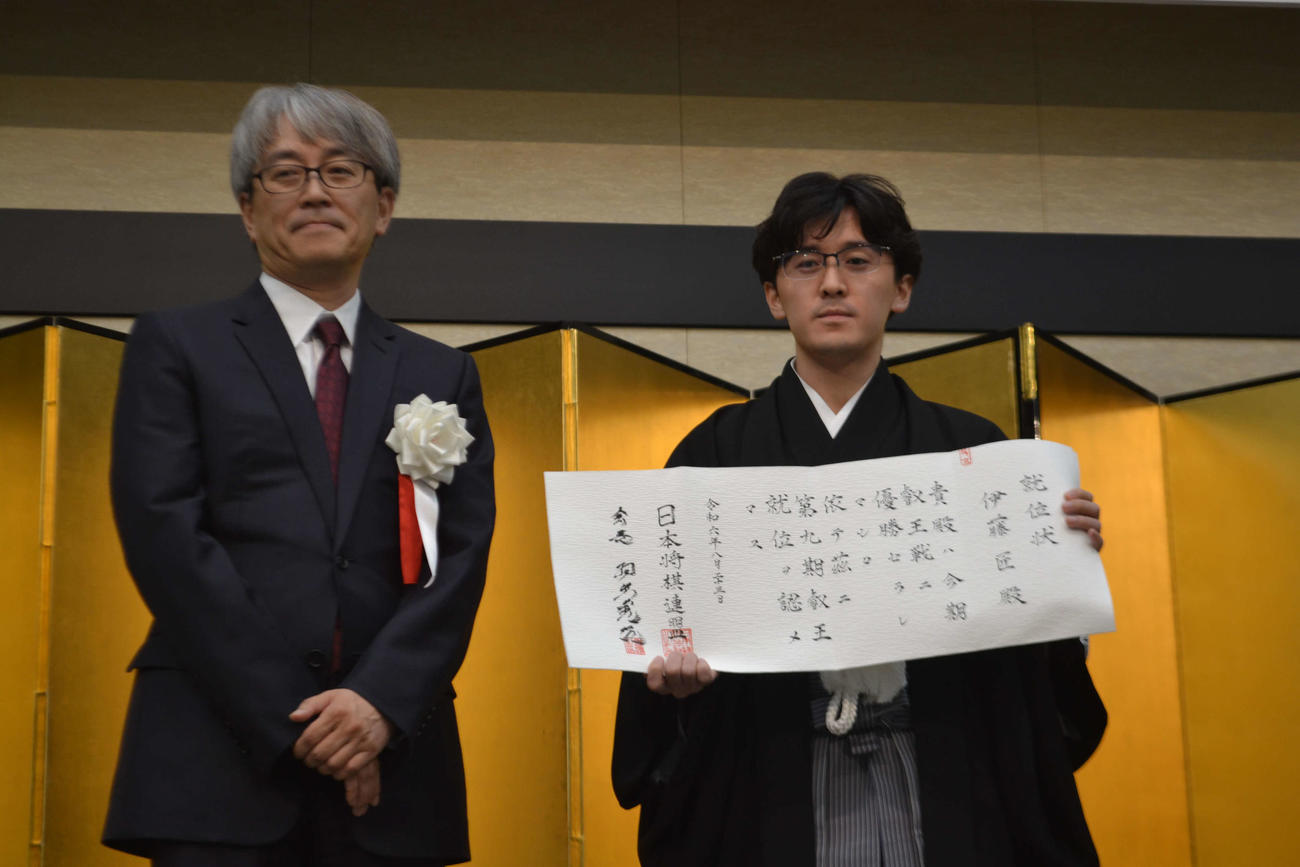日本将棋連盟会長の羽生善治九段（左）と並んで就位状を手にする伊藤匠叡王（右）