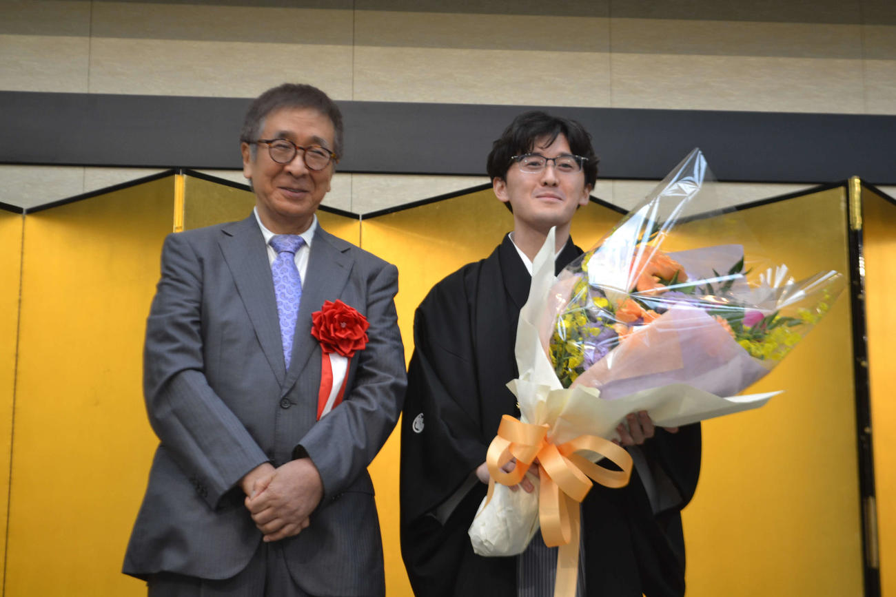 師匠の宮田利男八段（左）から贈呈された花束を手にする伊藤匠叡王（右）