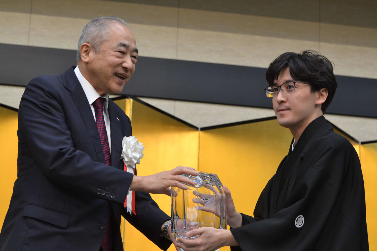 不二家の河村宣行社長（左）から賞杯を手にする伊藤匠叡王（右）
