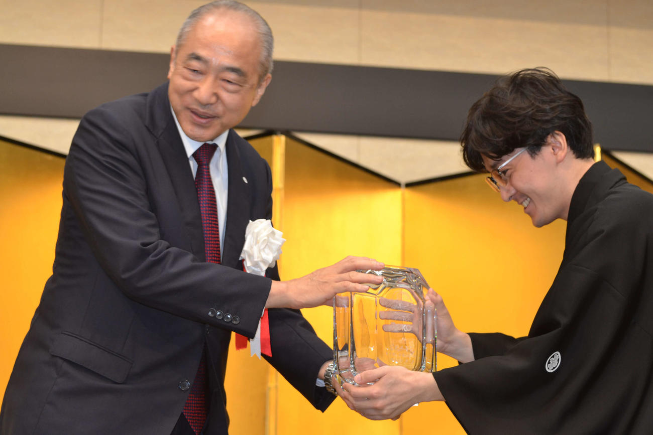 不二家の河村宣行社長（左）から賞杯を手にする伊藤匠叡王（右）
