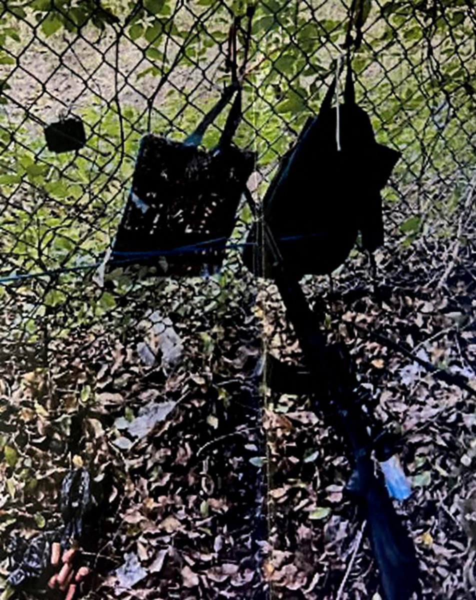 トランプ前大統領がプレーしていたゴルフ場のフェンスにかけられたリュックサックと自動小銃の写真。暗殺未遂事件後の撮影で記者会見時に提示された（ロイター）