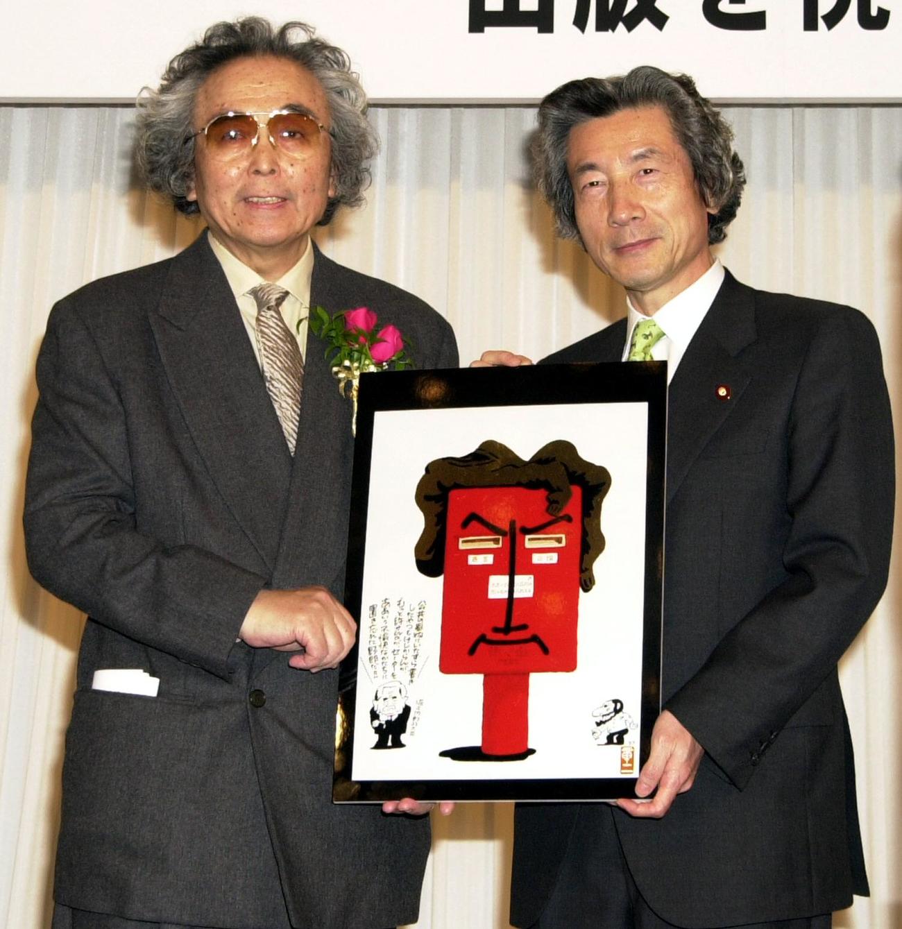 02年2月、「全体重」出版を祝う会で山藤章二さん（左）からイラストをプレゼントされる小泉純一郎首相