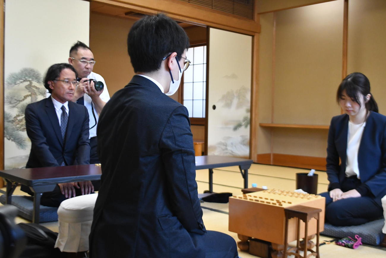 立会人の深浦康市九段（左）が対局開始告げて西山朋佳女流3冠（右）の編入試験第2局、山川泰熙四段戦がスタート