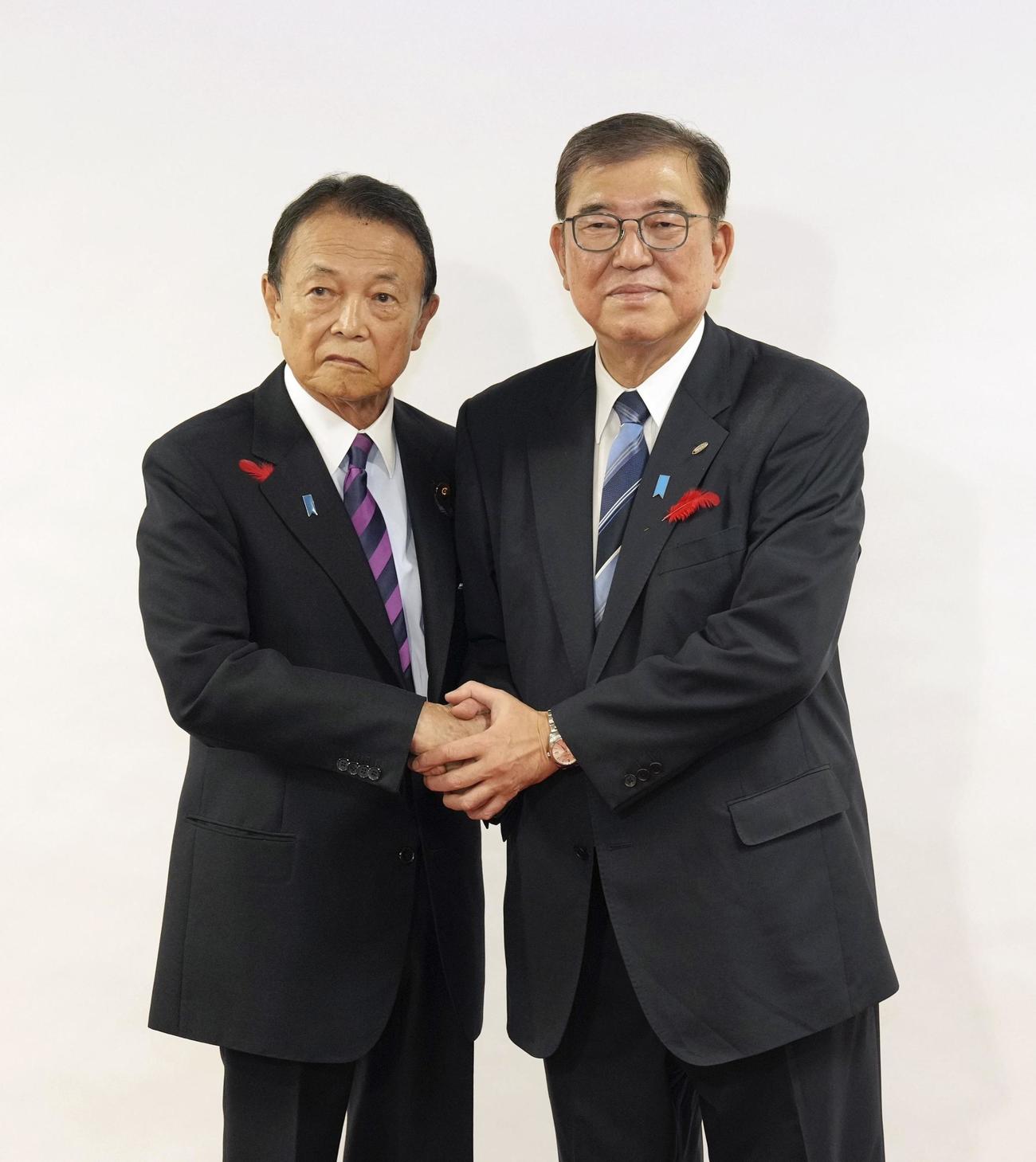 自民党本部で麻生最高顧問（左）に衆院選の公認証を交付し、握手する総裁の石破首相（共同）