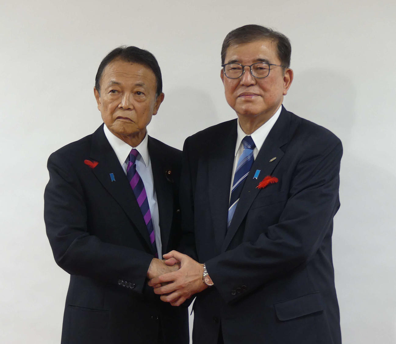 麻生太郎最高顧問（左）に衆院選の公認証を手渡した後、握手で写真撮影に応じる石破茂首相（撮影・中山知子）