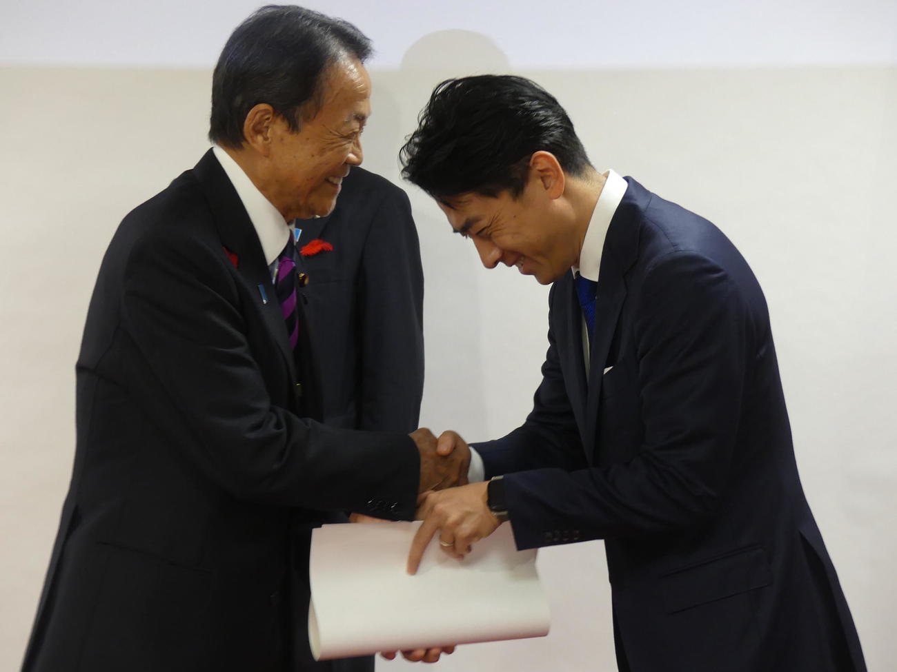 石破茂首相から公認証を受け取った後、小泉進次郎選対委員長（右）と笑顔で握手をかわす自民党のす麻生太郎最高顧問（撮影・中山知子）