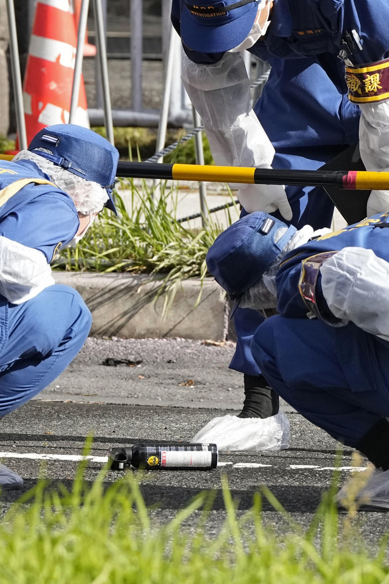 自民党本部前でスプレー缶のようなものを調べる捜査員＝19日午前8時58分、東京・永田町（共同）