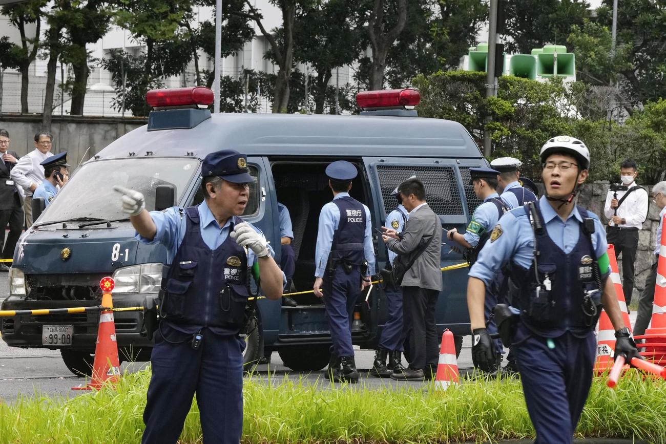 火炎瓶のようなものが投げ込まれ、騒然とする自民党本部付近。警察車両の前部が変色していた＝19日午前7時58分、東京・永田町（共同）