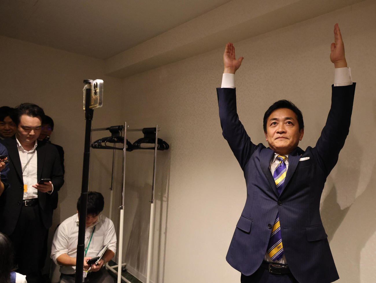 スマートフォンで地元選挙区と中継し当選確実をバンザイで喜ぶ国民民主党玉木雄一郎代表、カメラマンの希望に添ってカメラ目線でバンザイを行った（撮影・中島郁夫）
