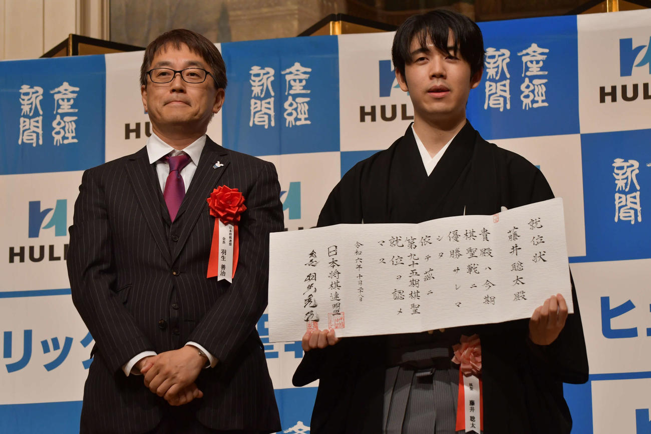 24年10月、日本将棋連盟会長の羽生善治九段（左）から贈られた就位状を手にする藤井聡太棋聖