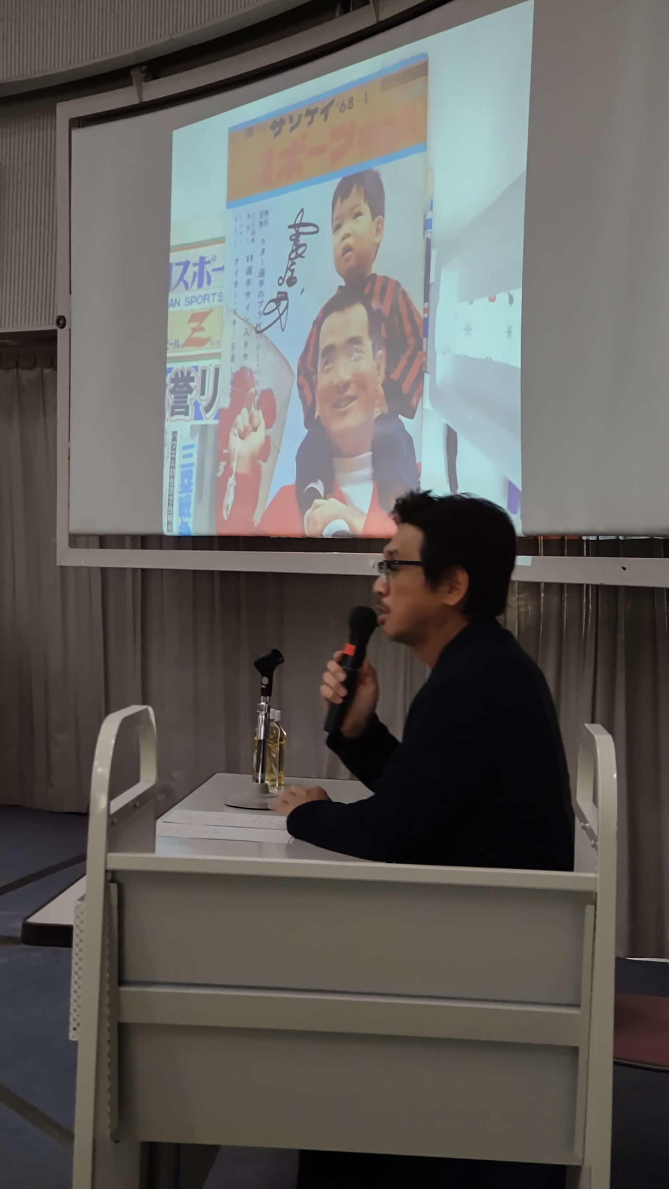 世田谷区立中央図書館で講演するやくみつるさん。長嶋一茂氏が初めて表紙を飾った雑誌のコレクションを披露する