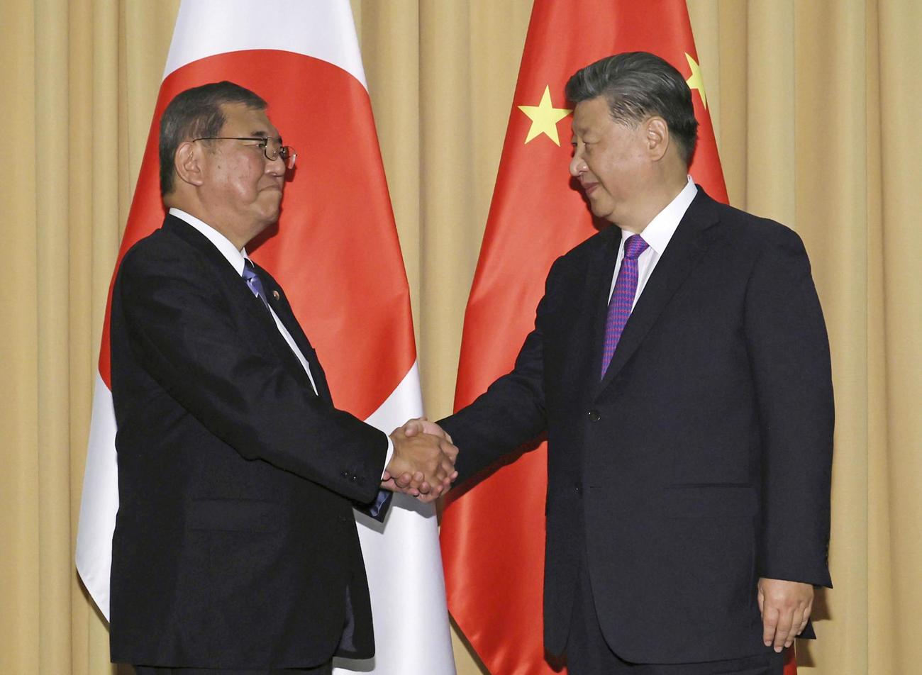 15日、首脳会談を前に握手する石破首相（左）と中国の習近平国家主席（代表撮影・共同）