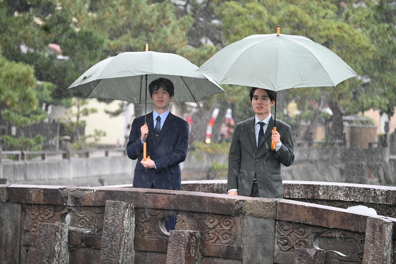 激しい雨と風の中、和歌の浦の「不老橋」から干潟を眺める藤井聡太竜王（左）佐々木勇気八段（撮影・松浦隆司）