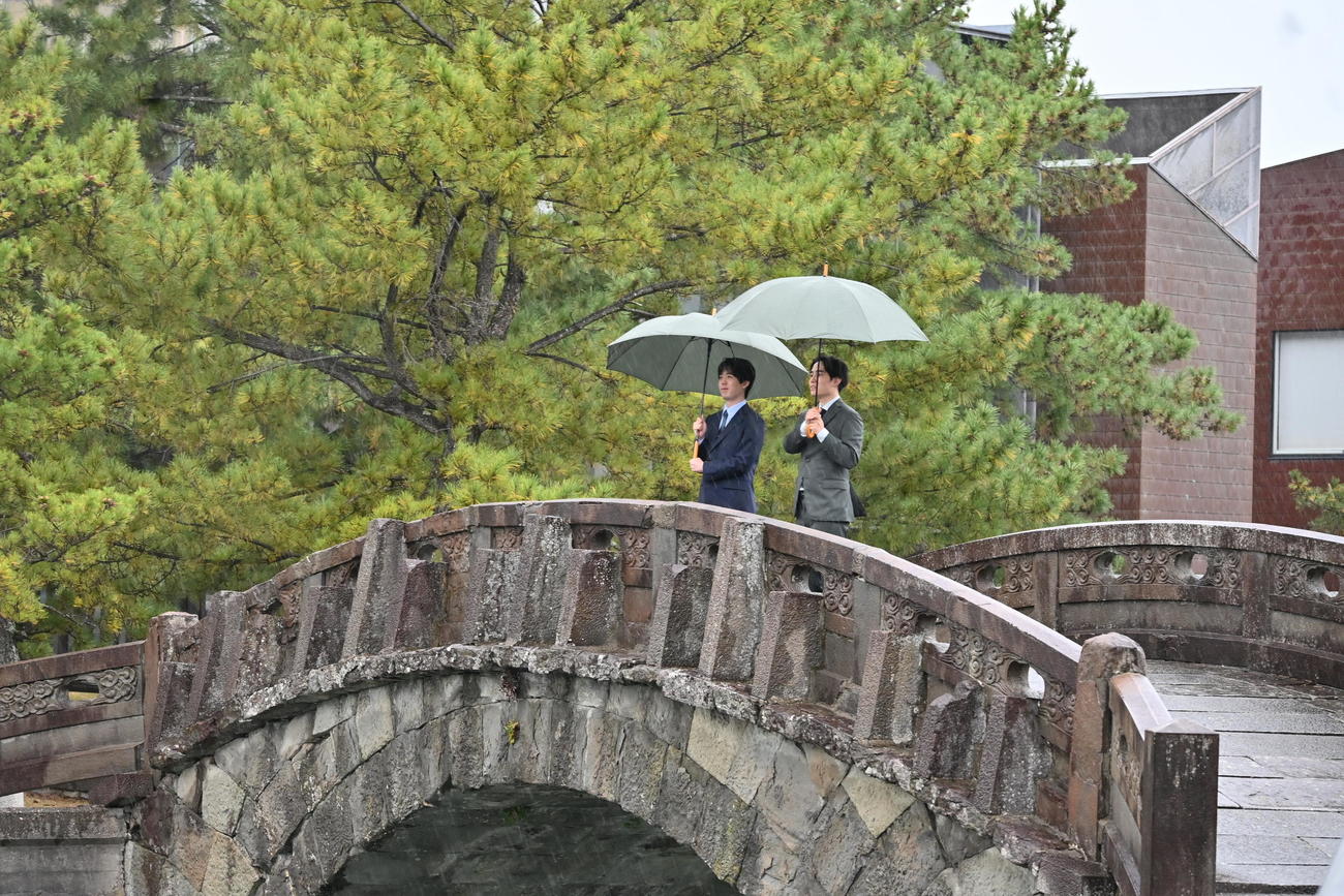 激しい雨と風の中、和歌の浦の「不老橋」から干潟を眺める藤井聡太竜王（左）佐々木勇気八段（撮影・松浦隆司）