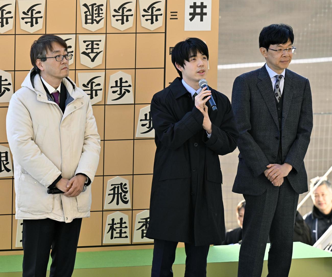 甲子園球場での記念対局を終え、観客にあいさつする藤井聡太七冠（中央）。左は羽生善治九段（共同）