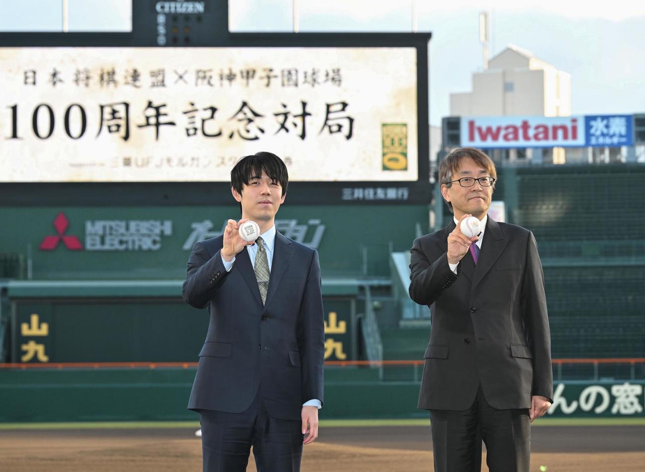 甲子園球場での記念対局を終え、記念写真に納まる藤井聡太七冠（左）と羽生善治九段（共同）