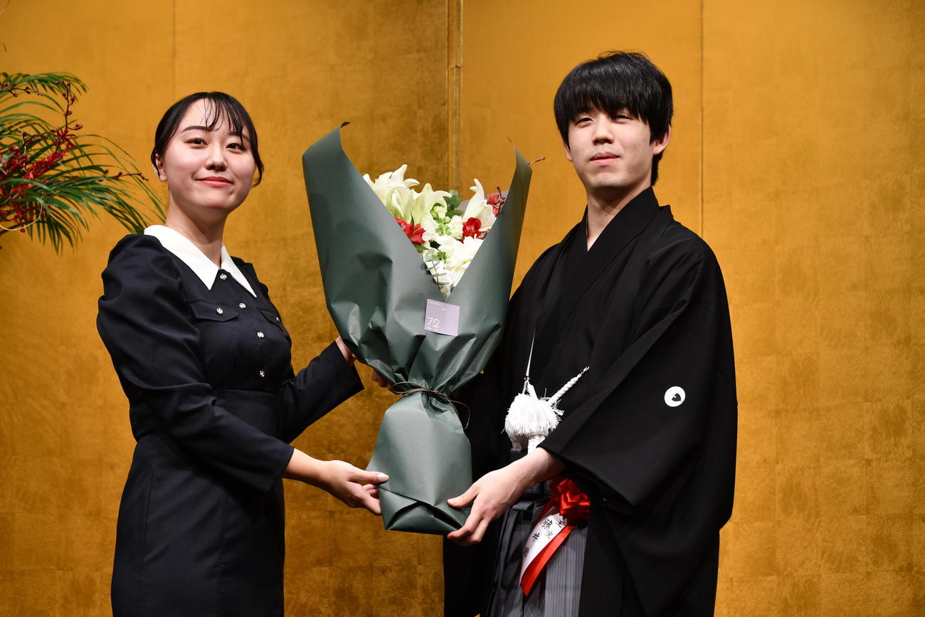 就位式で野原未蘭女流初段（左）から花束を贈呈される藤井聡太王座（右）