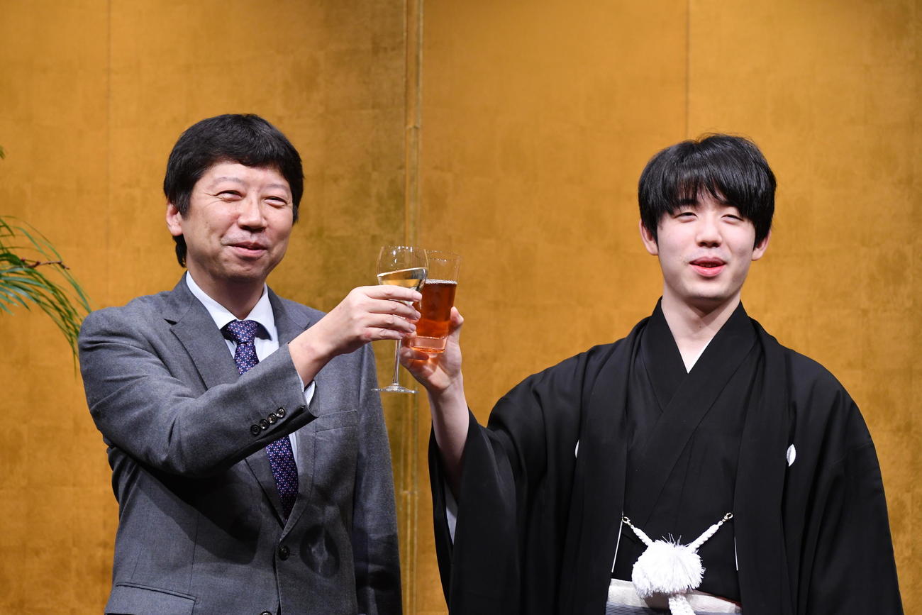 就位式で乾杯の発声を務めた師匠の杉本昌隆八段（左）とグラスを合わせる藤井聡太王座