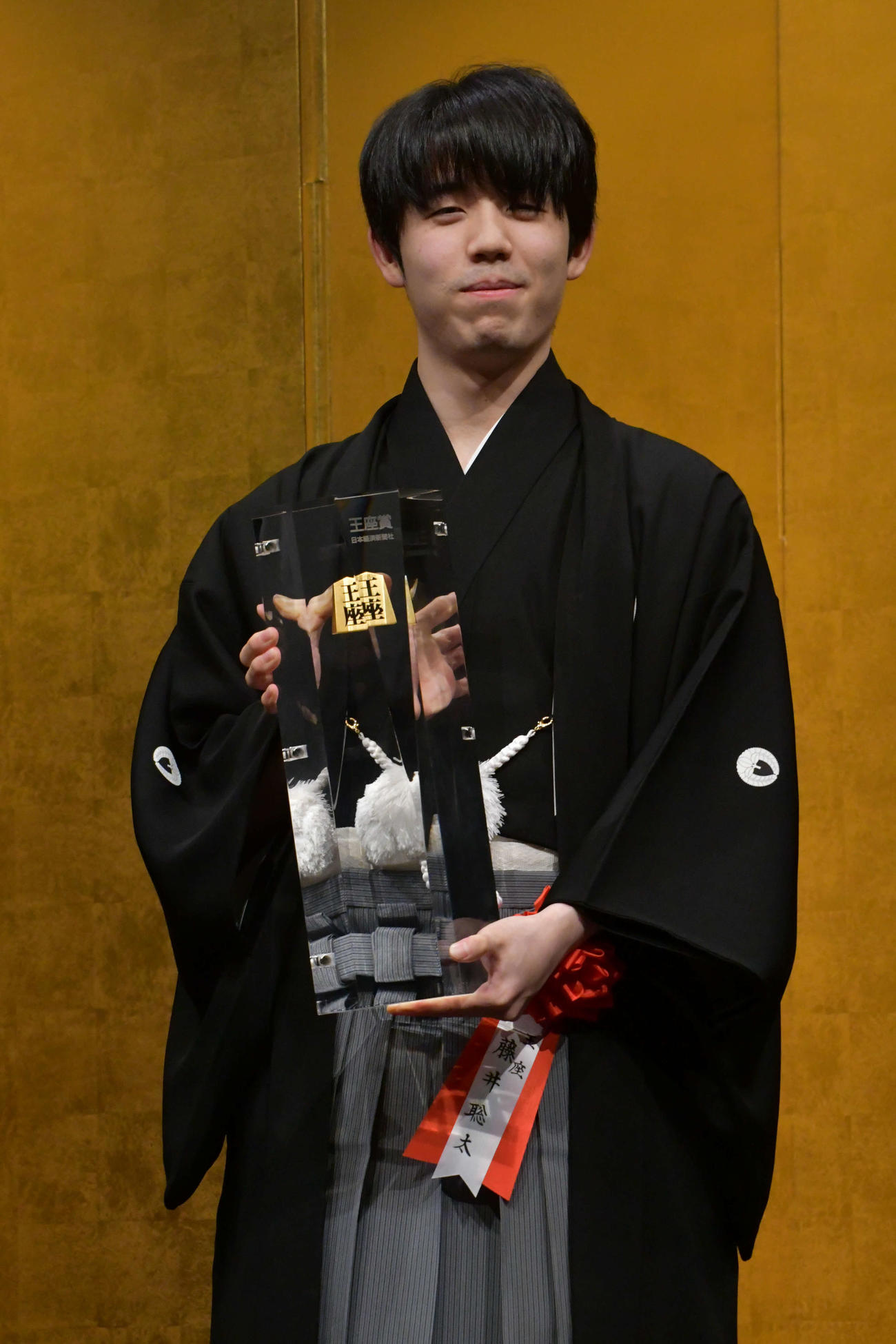 重さ7キロの王座賞トロフィーを手に持つ藤井聡太王座