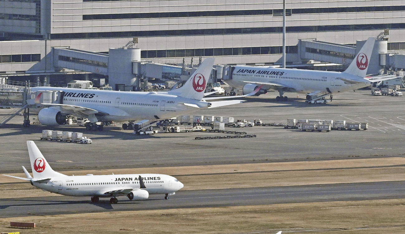 羽田空港のスポットに並ぶ日航機。システムの不具合が起き、一部の便に遅れが出た（共同通信社ヘリから）