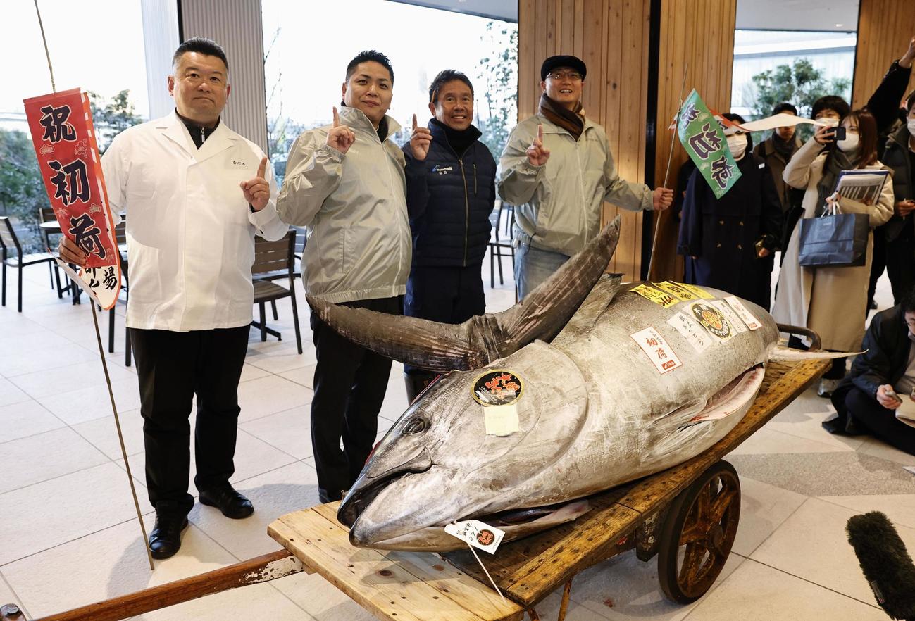 豊洲市場の「初競り」で、2億700万円の最高値で競り落とされた青森県大間産クロマグロ。左から3人目は写真に納まる「やま幸」の山口幸隆社長（共同）