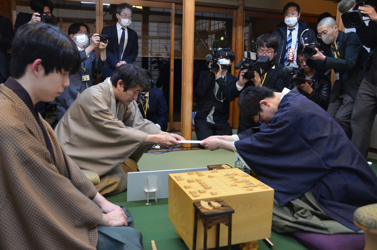 挑戦者の永瀬拓矢九段（右）が立会人の森内俊之九段（左から2人目）に封じ手の入った封筒を渡して初日が終了（左は藤井聡太王将、日本将棋連盟提供）