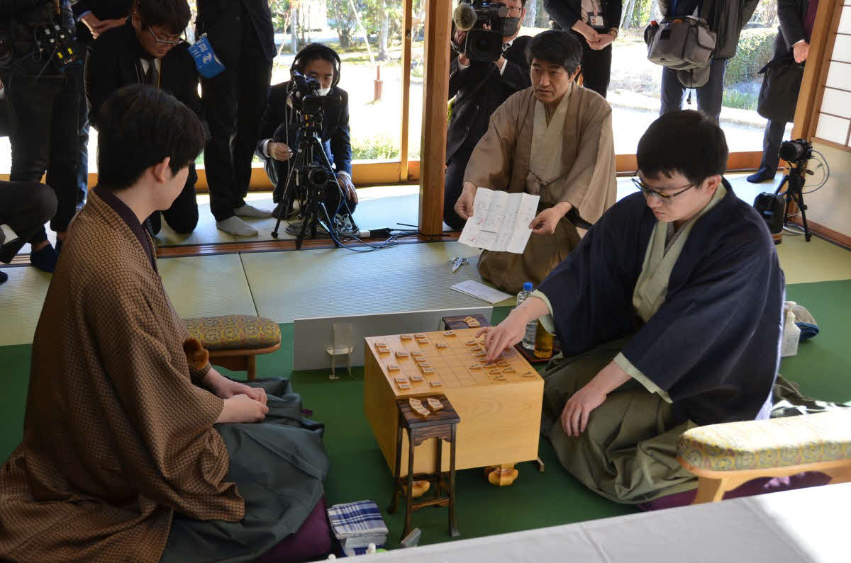 藤井聡太王将（左）に永瀬拓矢九段（右）が挑む王将戦第1局は立会人の森内俊之九段が封じ手を示して2日目が再開された（日本将棋連盟提供）