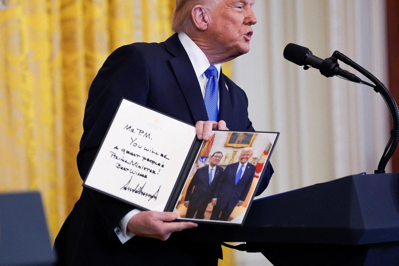 ホワイトハウスでの会見で石破茂首相との記念写真を見せるトランプ大統領（２０２５年２月７日、ロイター）