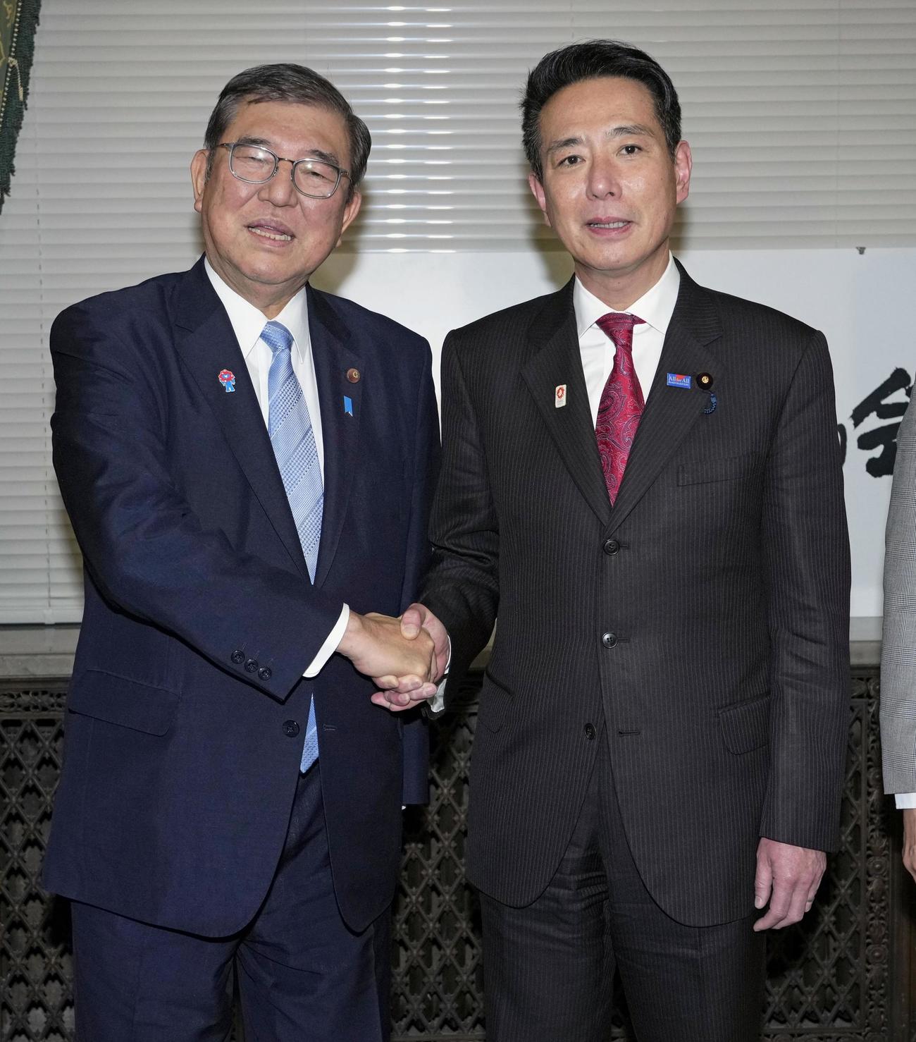 2025年度予算案の衆院通過後、日本維新の会控室をあいさつ回りで訪れ、前原共同代表（右）と握手する石破首相（共同）