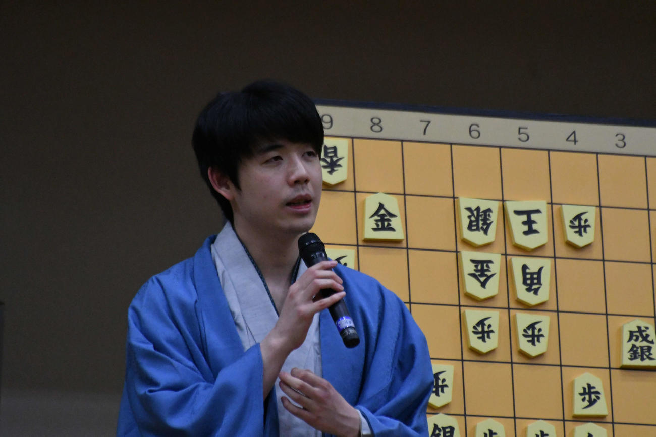 V4を決めて大盤解説会場であいさつする藤井聡太王将