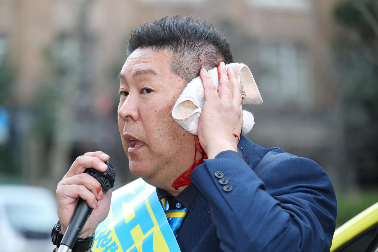 路上で暴漢に襲われ出血した状態でマイクで襲われた状況などを話す立花孝志氏（撮影・中島郁夫）