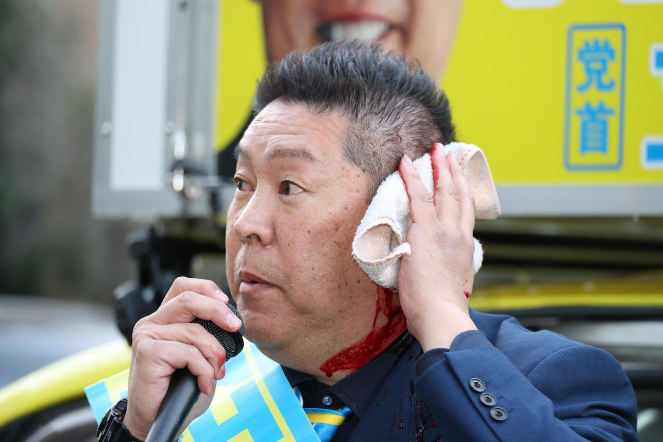 路上で暴漢に襲われ出血した状態でマイクで襲われた状況などを話す立花孝志氏（撮影・中島郁夫）