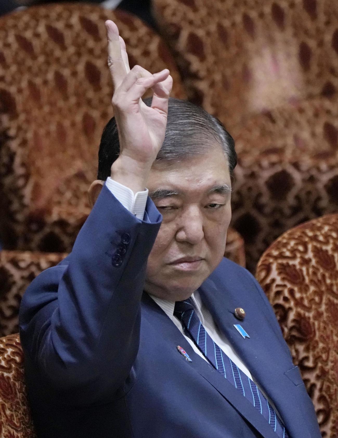 参院予算委の集中審議で答弁のため手を挙げる石破首相＝19日午前