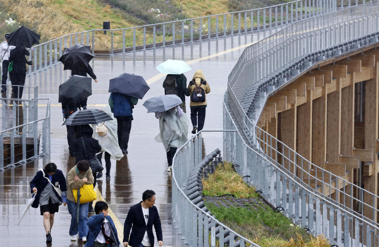 大阪・関西万博が開幕も、大荒れの天気の中、大屋根リングを歩く人たち（撮影・藤尾明華）