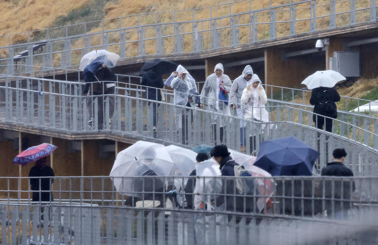大阪・関西万博が開幕も、大荒れの天気の中、大屋根リングを歩く人たち（撮影・藤尾明華）