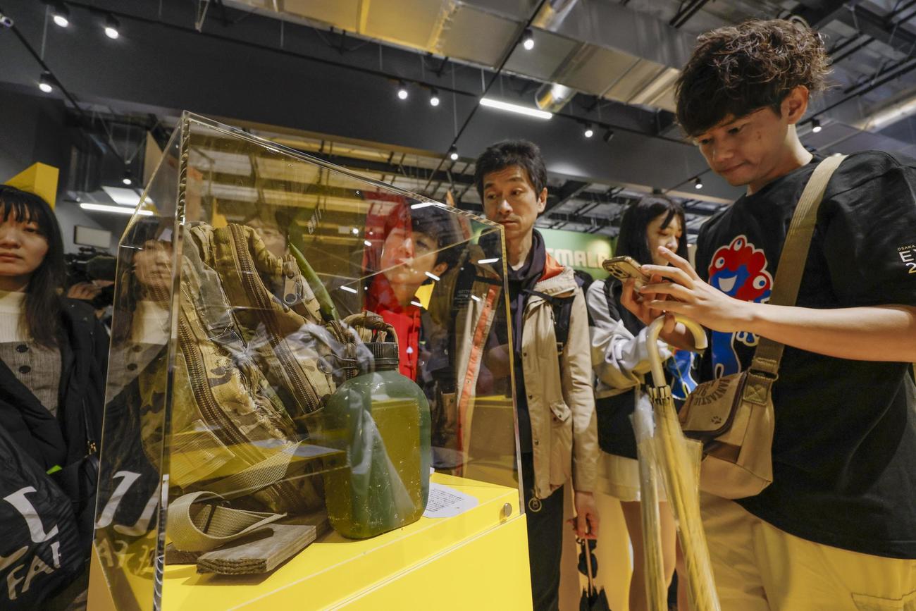 ウクライナのブースで兵士のリュックサックの展示を見る来場者（共同）
